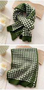 Detail of knitted heart pattern scarf in dark green and white with ribbed edges