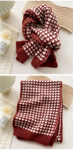 Detailed knit texture of red and white heart-patterned scarf with warm ribbed edges