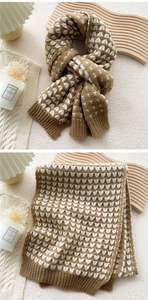 Detail of warm khaki knitted scarf with white heart jacquard and soft wool texture