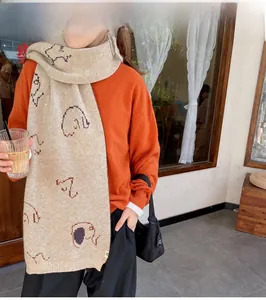 Detail shot of a beige knit scarf with artistic elephant patterns on a female model