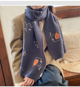 Detail of dark blue knit scarf with pixel-art animal patterns and soft texture