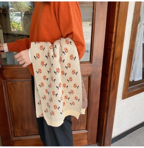 Detail of knitted scarf with orange floral pattern and ribbed edge texture in close-up