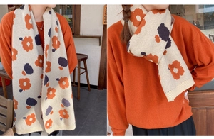 Detail of knitted floral scarf with ribbed edges and soft cream texture for winter