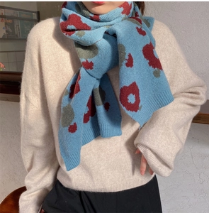 Detail of blue knitted scarf with red and grey jacquard pattern showing soft texture