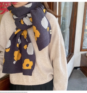 Close-up of thick knitted winter scarf featuring vibrant yellow and white flower patterns
