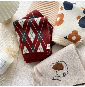 Flat lay of knit scarves with diamond check and floral patterns in warm Nordic style