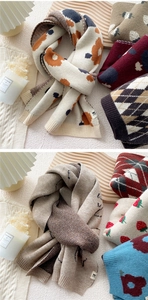 Close-up of thick knitted winter scarves featuring floral, plaid, and polka dot patterns