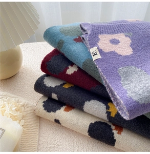 Detail of soft knit scarf with floral jacquard patterns and elegant woven labels