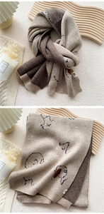 Detail of soft knit scarf with elephant pattern and ribbed edges in beige and brown