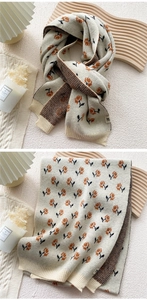 Detail of floral knit scarf showing orange flower patterns and soft ribbed edges