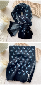 Detail of knit scarf with blue rose patterns and signature F label for winter