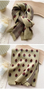 Close-up of green knit scarf with red strawberry patterns and ribbed edge detail