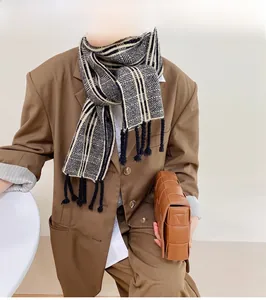 Gros plan d'une écharpe en maille à carreaux noir et blanc avec franges sur un blazer