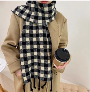 Détail d'une écharpe en maille à carreaux noirs et blancs avec franges sur un manteau