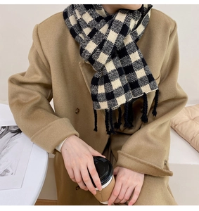 Détail d'une écharpe à damier avec franges portée sur un manteau en laine