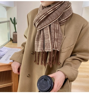 Détail d'une écharpe en tricot à carreaux marron avec franges sur un manteau
