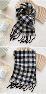 Détail d'une écharpe en maille à carreaux noirs et blancs avec texture douce et glands à la main