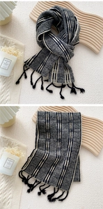 Détail d'une écharpe en maille à carreaux avec franges, aux rayures noires, blanches et grises