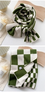 Detail of green and white checkered knit scarf showing thick texture and wash label