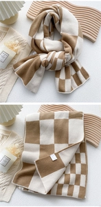 Detail of checkered knit scarf showing soft thick texture and warm brown-cream pattern