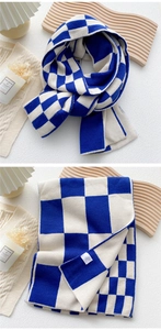 Close-up of blue and white checkered knit scarf with thick winter texture and label