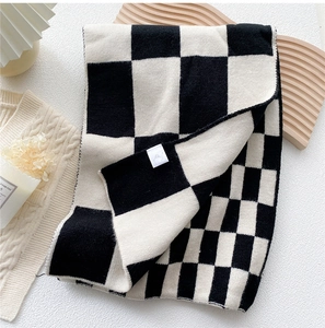 Macro detail of black and white checkerboard knit scarf texture with a brand logo tag