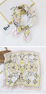 Detail of a square silk scarf with paisley patterns and a soft satin finish on a white base