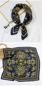 Detailed view of square silk scarf with yellow paisley patterns and geometric borders