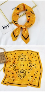 Detail of yellow paisley silk square scarf shown tied and styled on a straw bag