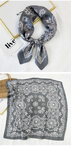 Close-up of grey silk scarf with white paisley pattern and elegant knotted styling