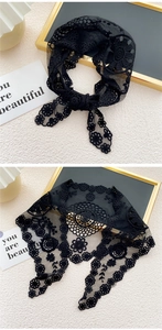 Détail d'une écharpe en dentelle florale noire avec broderie ajourée et bords festonnés