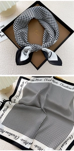 Detail of silk square scarf with houndstooth pattern and brand print in a gift box