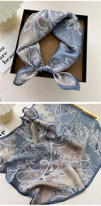 Detail of paisley silk scarf in grey-blue with elegant floral patterns in a black gift box