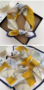 Macro detail of geometric print silk scarf in gift box with yellow and blue patterns