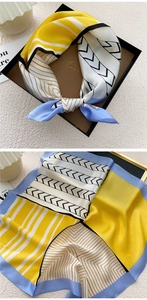 Detail of geometric pattern silk scarf with bold yellow and blue colors in a gift box