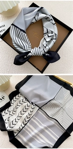 Detail of silk square scarf in geometric black and white patterns inside a gift box