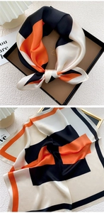 Close-up of geometric orange and black silk scarf with refined edge stitching details