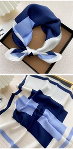 Detail of silk square scarf featuring blue geometric patterns and smooth glossy texture