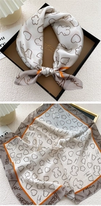 Detailed view of silk square scarf featuring bear patterns and orange border in a gift box