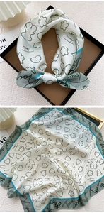 Detailed close-up of beige silk scarf featuring bear motifs and green border accents