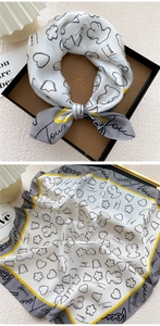 Detail of square silk scarf with floral bear print and yellow borders in a gift box