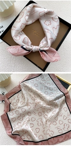 Close-up of silk square scarf featuring bear silhouette patterns and branded logo design