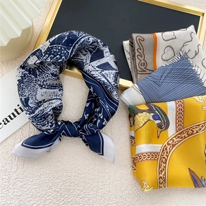 Silk-like square scarf with floral and geometric patterns shown on elegant props