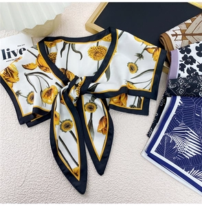 Close-up of elegant silk-feel shawl scarf with yellow daisy print and knotted design