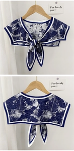 Close-up of navy blue leaf print shawl with white piping and ribbon bow tie design