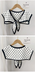 Detail of white decorative collar shawl with black D-letter print and tie-up design