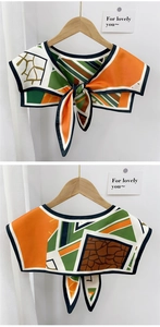 Detail of geometric pattern silk scarf collar with tie-knot design on wooden hanger
