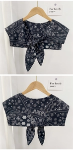 Detail of paisley print detachable shawl wrap with a front bow tie on a wooden hanger