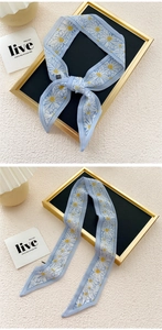 Detail of light blue daisy print narrow silk scarf with fine stitching and soft texture