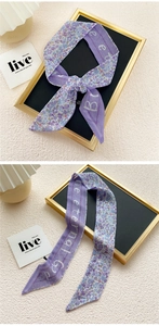 Detail of purple floral scarf tied in a bow with 'Eternal God' print on polyester fabric